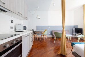 A modern kitchen with a microwave, oven, and dining area with chairs and a table.