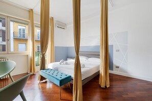 Un dormitorio con cama, una banca, cortinas y una ventana con vistas a edificios.