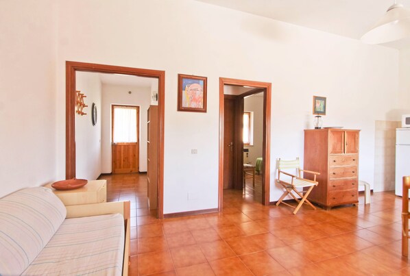 A spacious living area with a sofa, wooden cabinet, and a director's chair. - Apartment with terrace and garden, few meters far from the lake (grotte di castro)