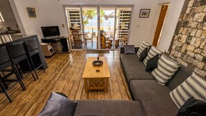 Een woonkamer met een bank, gestreepte kussens, een houten salontafel en een televisie.