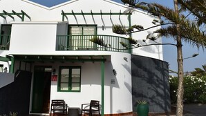 Um edifício de dois andares com fachada branca, detalhes em verde e uma varanda.