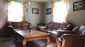 A living room with two brown leather sofas, a wooden coffee table, and floral curtains.