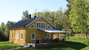 A yellow wooden house with a balcony, a chimney, and a satellite dish.