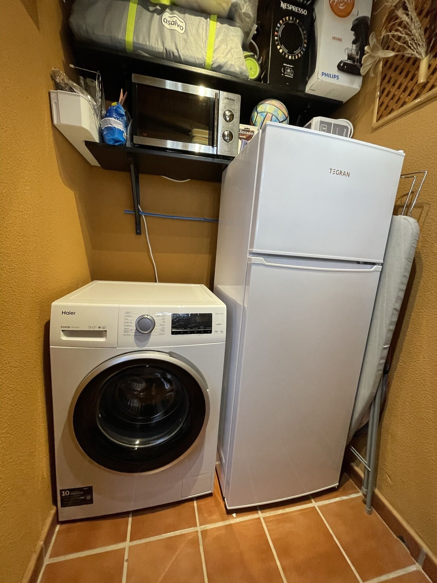 A compact laundry area with a Haier washing machine and a white Frigidaire refrigerator.