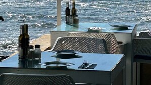 Une table avec des bouteilles et des verres, donnant sur une côte rocheuse.