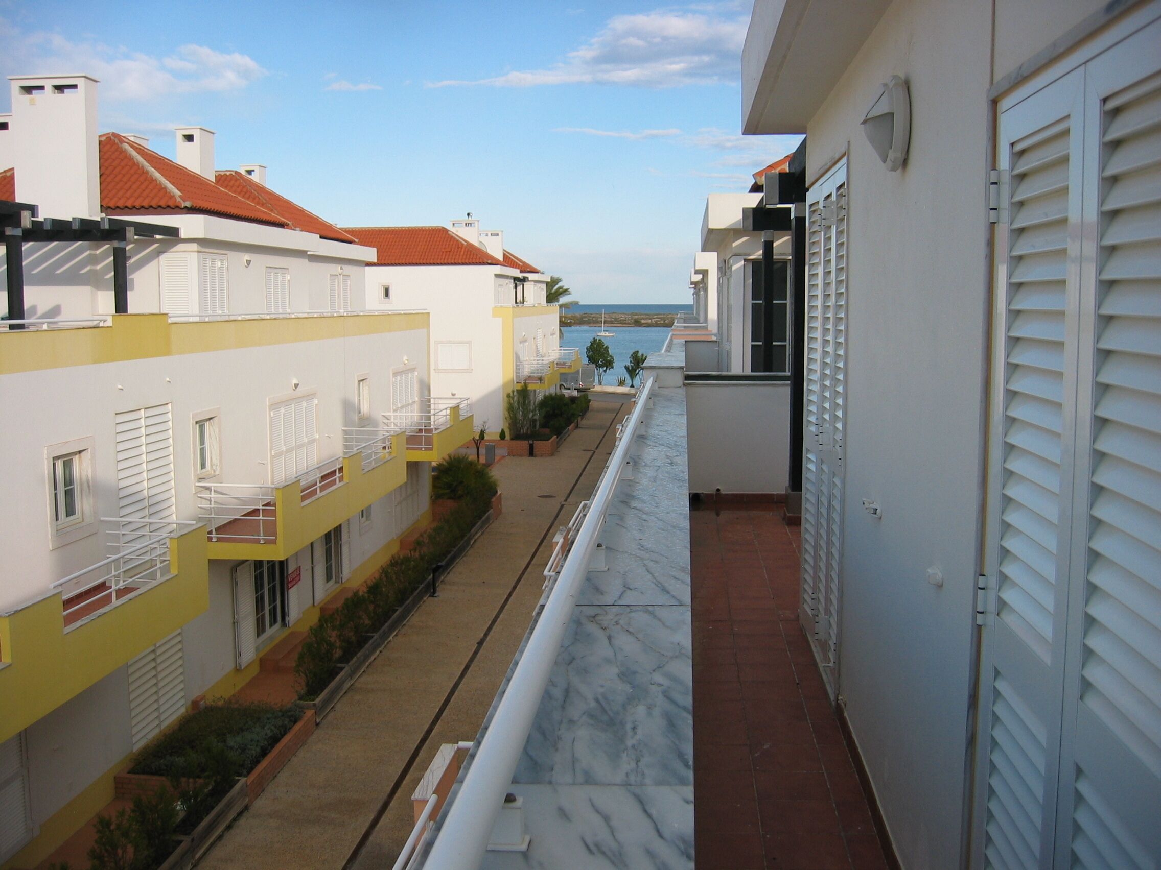 Un balcon étroit offrant une vue sur la mer et les bâtiments avoisinants.