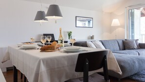 Zona pranzo con tavolo apparecchiato per due, divano e quadro appeso al muro.