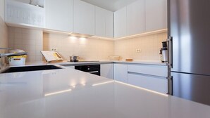 Una cucina moderna con mobili bianchi, un frigorifero in acciaio inossidabile e un'isola centrale.