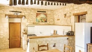 A rustic kitchen with stone walls, a wooden table, and chairs.