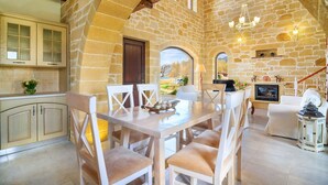 A spacious dining area with a stone wall backdrop, a fireplace, and a view of the outdoors. - LUXURY VILLA POSIDONIA with Pool only 35 metres from the beach.  (Chania)