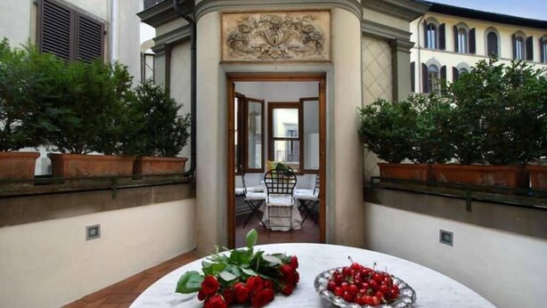 A courtyard with a marble table, potted plants, and a view of an interior dining area. - Luxury Apartment in Florence "TERRAZZA DE' MEDICI" (Firenze)