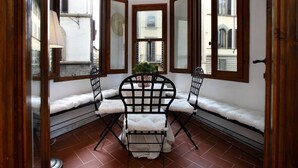 A corner room with a bed, two chairs, a small table, and a potted plant. - Luxury Apartment in Florence "TERRAZZA DE' MEDICI" (Firenze)