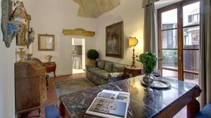 A room with a marble table, a sofa, a chandelier, and a view through a window. - Luxury Apartment in Florence "TERRAZZA DE' MEDICI" (Firenze)