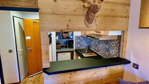 Eine kleine Küche mit Holzwand, einer Mikrowelle, einem Toaster und einem Waschbecken.