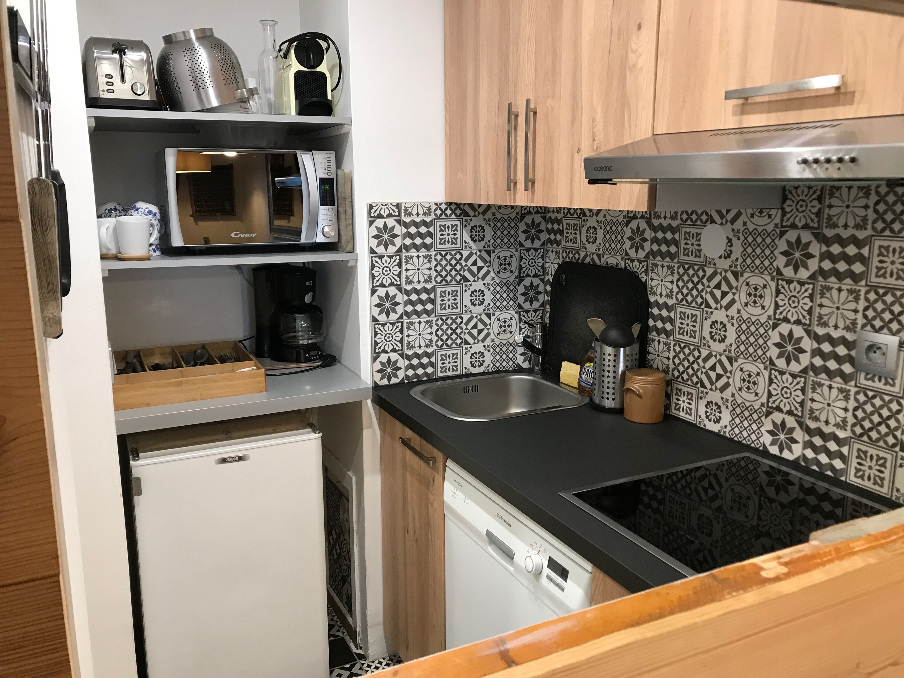 A compact kitchen with a microwave, toaster, coffee maker, and a sink.