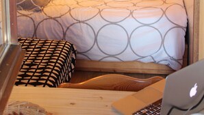 Ein gemütliches Zimmer mit einem Holz-Kopfteil, einem Bett mit gemusterten Betttextilien, einem Laptop auf dem Boden und einer sternförmigen Dekoration.
