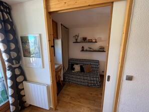 A cozy room with a patterned sofa, a wooden chair, and a radiator. - At the foot of the slopes in the Alpes d'Huez, very nice comfortable apartment (Huez)