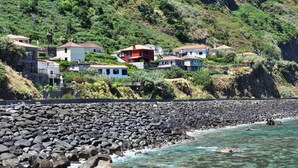 Uma vila costeira com casas construídas numa encosta com vista para o mar.