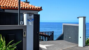 Um imóvel à beira-mar com telhado em cerâmica, portão fechado e vista para o mar.
