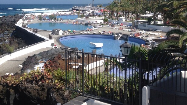 A coastal resort with a large swimming pool, beach area, and ocean view.