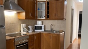 A compact kitchen with wooden cabinets, a stainless steel stove, a microwave, and a sink.