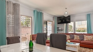 Un salon moderne avec un canapé rouge, une table basse blanche et une table à manger sur laquelle se trouve une bouteille de champagne.