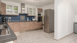 Une cuisine moderne avec des meubles en bois, un réfrigérateur en acier inoxydable et un four à micro-ondes.