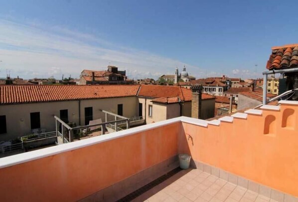 A rooftop terrace with a view of surrounding buildings, including a church with a dome.