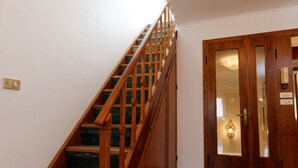 A staircase with wooden railings and a patterned floor leading to a door with a glass panel. - Apartment A. Cà Canziani - On the roof in Venice (Venezia)