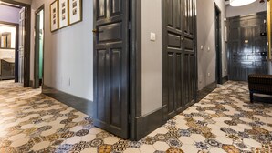 Un pasillo con puertas de madera oscura, baldosas de piso con diseños y un banco.