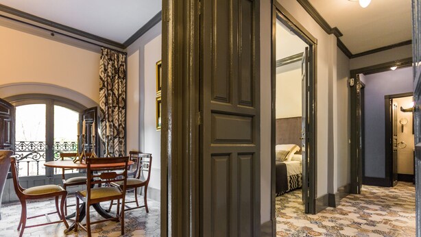 Habitación con zona de comedor que incluye una mesa y sillas, suelo estampado y una puerta que da a otra habitación.