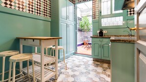 Una cocina con armarios verde azulado, encimera blanca y piso estampado.