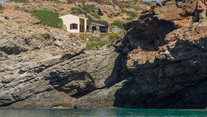 Ein Küstenhaus mit Felsküste im Hintergrund, in der Nähe eines Gewässers gelegen.
