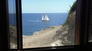 Ein Segelboot auf dem Meer, im Hintergrund eine felsige Küste.
