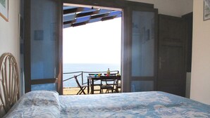 Ein Schlafzimmer mit Bett, Blick auf den Strand und einem Tisch mit Stühlen im Freien.