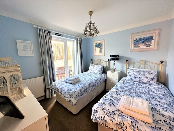 A bedroom with two beds, a chandelier, a framed picture, and a fire exit sign.