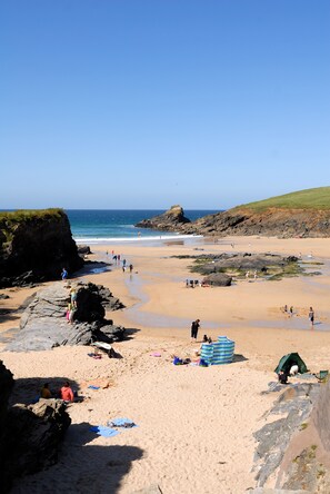 A beach with people, tents, and a rocky coastline.