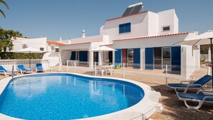 A swimming pool with lounge chairs, a white building with blue shutters, and a clear blue sky. - Casa do Farol – Cozy Retreat with Special Rates in Low Season Algarve (Carvoeiro)