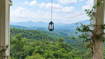 An outdoor seating area with a table and chairs, overlooking a mountainous landscape.