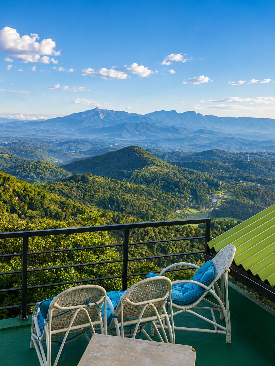 Een terras met rieten stoelen en een tafel, met uitzicht op een bergachtig landschap.