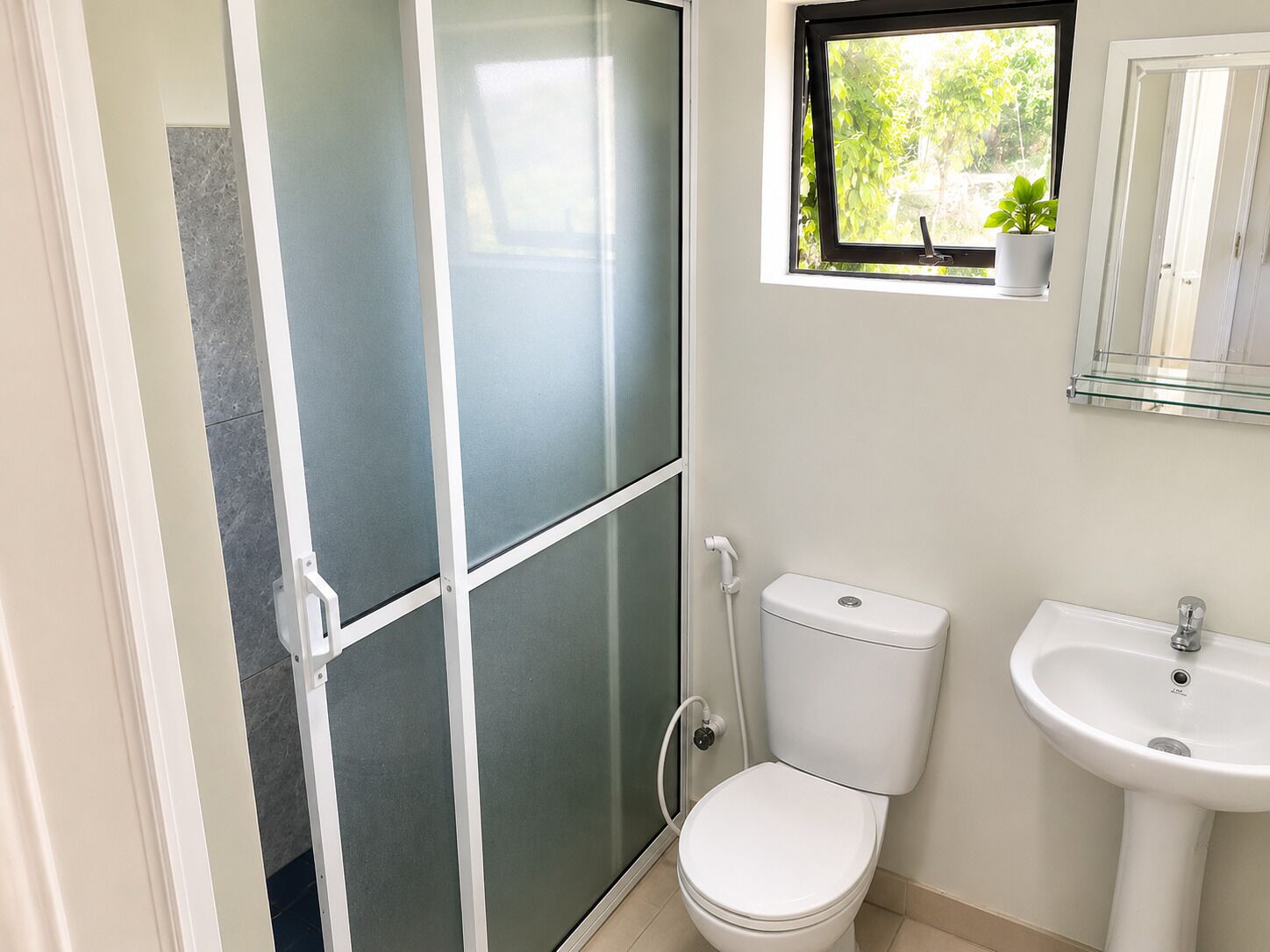 A bathroom with a toilet, a sink, and a shower enclosure.