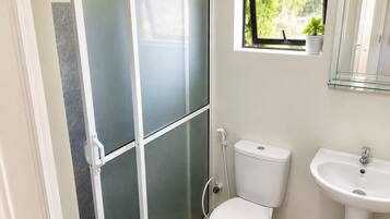 A bathroom with a toilet, a sink, and a shower enclosure.