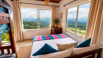 A bedroom with a bed, pillows, a nightstand, and a window with a view of the landscape.