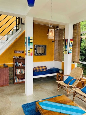 A room with a sofa, a chair, a bookshelf, and a staircase.