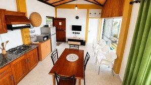 A compact kitchen with a dining area, wooden cabinets, a stove, and a TV. - Your Private Mountain Escape in Kandy - Eagles' Nest (Moragolla)