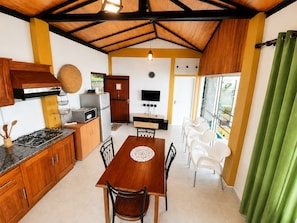 A compact kitchen with a dining area, wooden cabinets, a stove, and a TV.