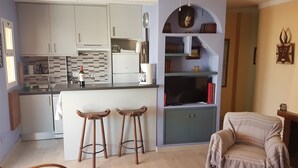 A compact kitchen with white cabinets, a coffee maker, and a wine bottle. There are two wooden stools in front of the counter. - Large sunny terrace, 6à m from the beach; large and comfortable (Fuengirola)