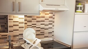 A modern kitchen with white cabinetry, a black countertop, a built-in dishwasher, and a compact stove. - Large sunny terrace, 6à m from the beach; large and comfortable (Fuengirola)