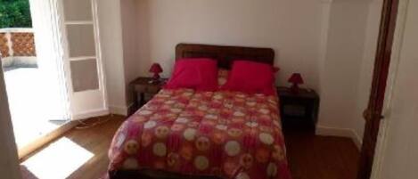 Quarto com cama de madeira, duas mesas de cabeceira e uma janela grande.