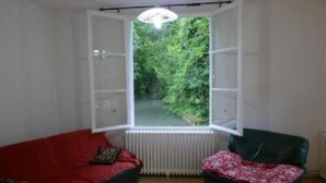 A room with a large window, a radiator, a red sofa, and a green armchair. - Mansion - BERGERAC (Bergerac)